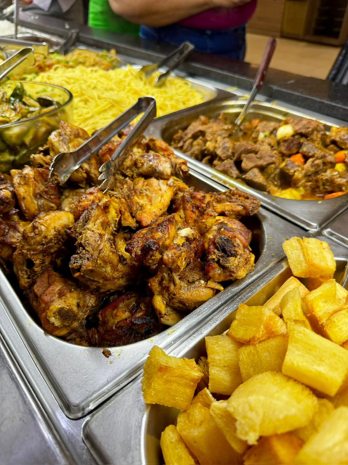Foto real de comida caseira no buffet do Dom Ramalho, com frango, acompanhamentos e mandioca